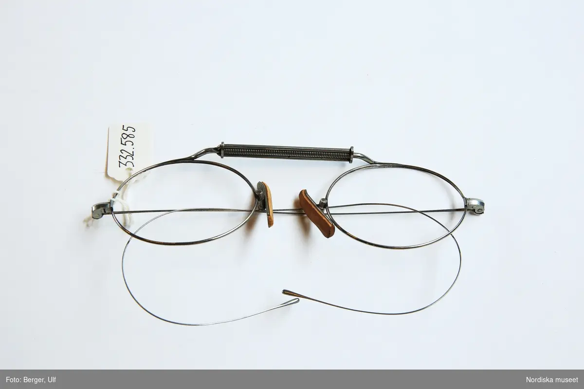 Pincenez-glasögonbågar av förnicklat stål, med massiva ridfjädrar och en spiralpincenez, även benämnd horisontal-pincenez, med korkklädda gungsadlar. För ovala glas, 38 x 29 mm.
/Optikhistoriska museets katalog