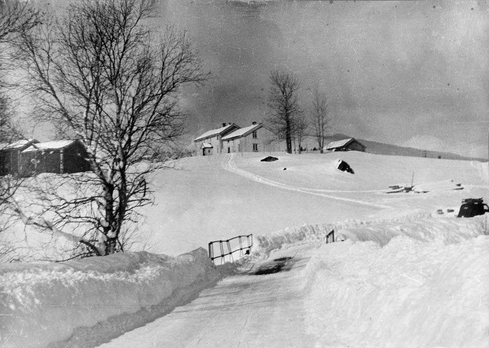 Gårdsplass på Strauman dekket av snø. Liten bro. Hvitt hus.