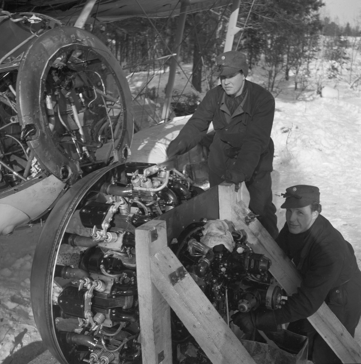 Demontering av motor på flygplan Gloster Gladiator efter Finska vinterkrigets slut i mitten av mars 1940 vid Svenska frivilligkåren i Finland, F 19. Två militärer i arbete.