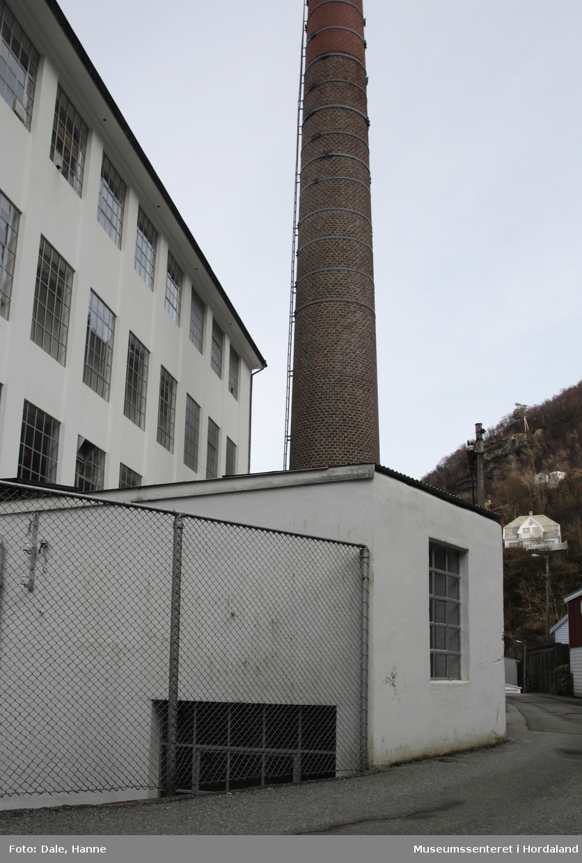 Del av produksjonslokala til Salhus Tricotagefabrik (1859-1989) bygd i 1903. Fyrhus og skorstein til fabrikken, med oljekjel i eitt rom, fyrkjel i den andre delen, og fabrikkskorsteinen.