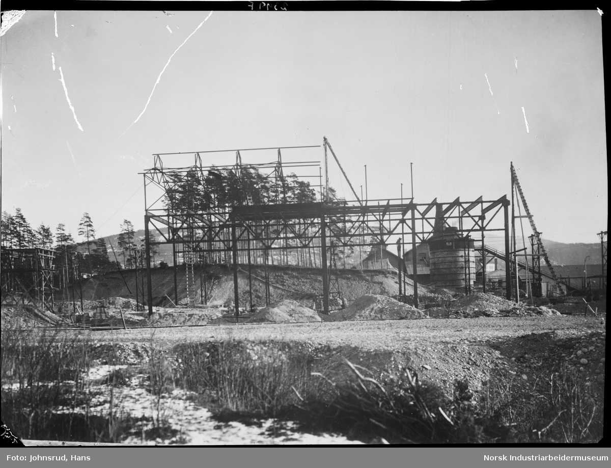 Bygging av Tinfos papirfabrikk på Nesøya. Pipa på Notodden Calcium-Carbidfabrikk i bakgrunnen.