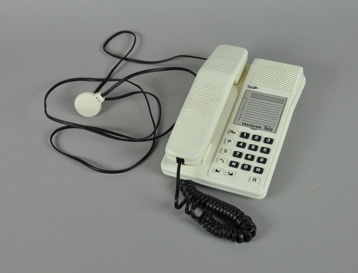Bordtelefon med hvitt plastdeksel og svart spiralledning.