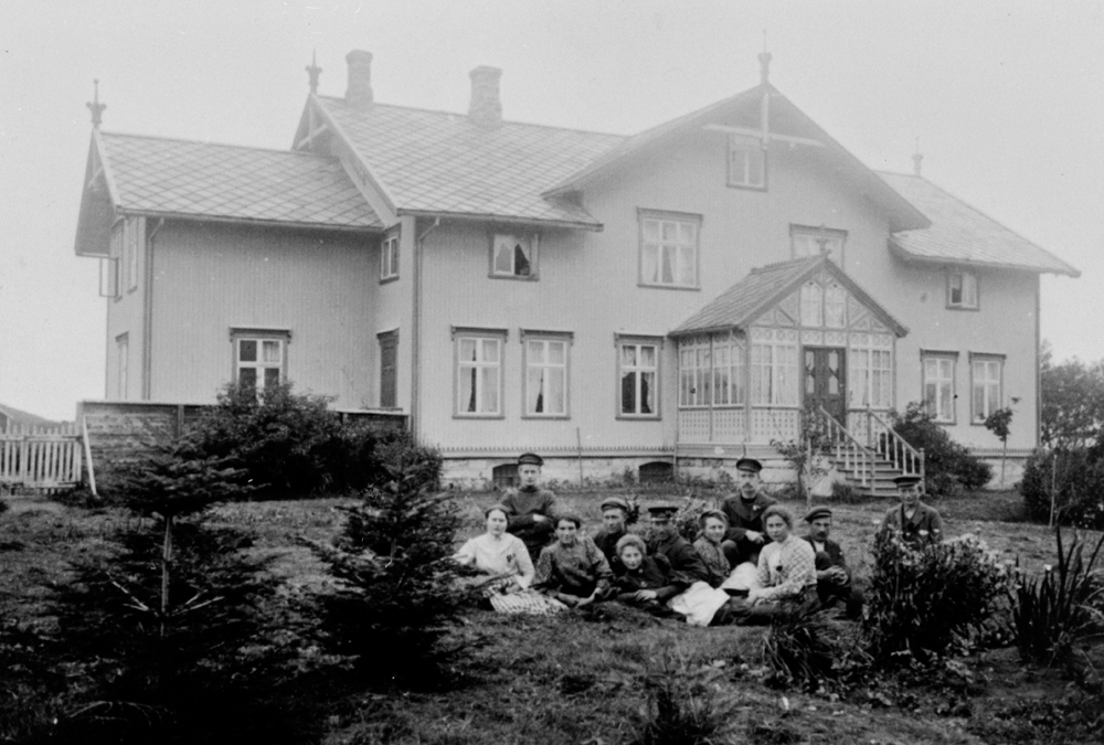 Hovedbygningen på Dønnes gård oppsatt i 1890, bildet er tatt i 1907. Gruppe sittende på plenen foran.