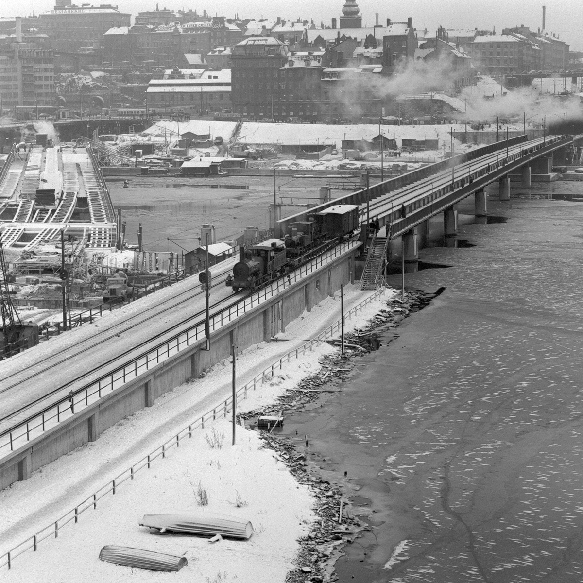Statens Järnvägar SJ 1856-1956. 100-årsjubileum. Tåg med gamla lok och vagnar vid Södra Järnvägsbron på sträckan mellan Riddarholmen och Mälarstrand. Bergslagernas Järnvägar BJ K 27.
