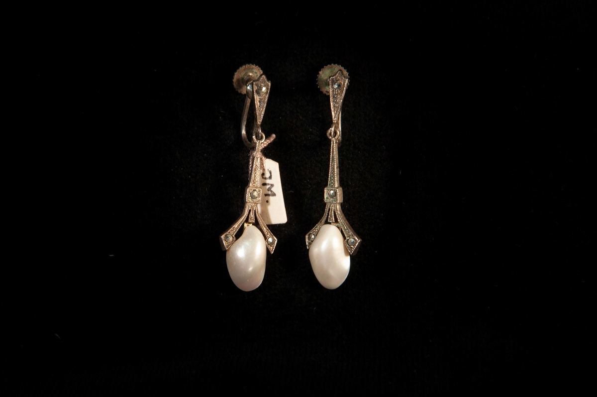 Ett par öronhängen. Genombrutna örhängen av silver med infattad halv pärla och så kallade stålbriljanter. Senjugend. Skruvmodell.