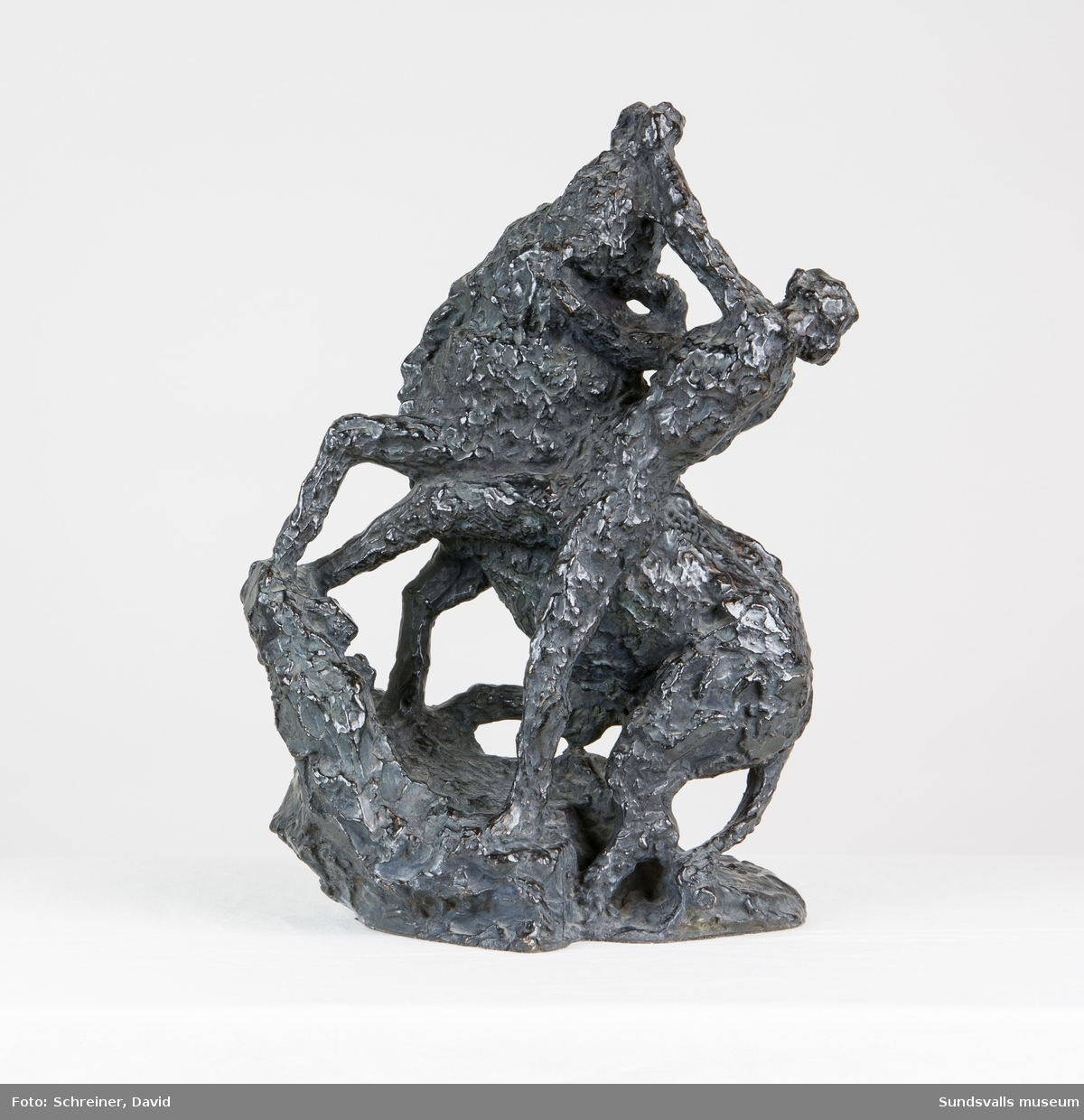 En skulptur i form av en man i kamp med en tjur där mannen i en kraftfull rörelse tvingar tjurens huvud uppåt och bakåt.