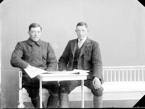 Bröderna Carlsson. Två unga män sittande i soffa vid ett bord, Elfin till vänster och Gunnar till höger.