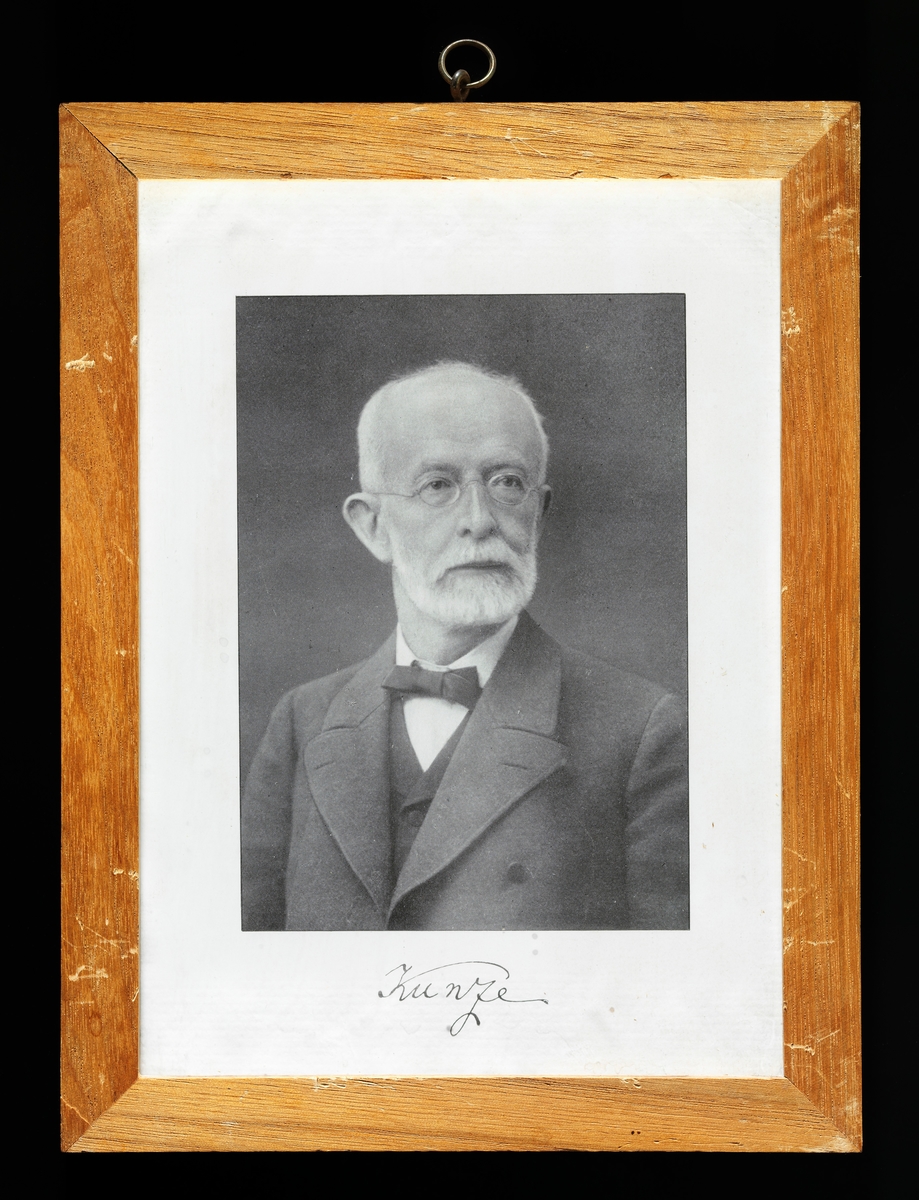 Litografisk gjengivelse av portrett av forstmannen Max Friederich Kunze (1838-1921) med hans navnetrekk under.  Kunze er fotografert i et studio, kledd i mørk dress med vest og kvit skjorte under.  I halsen hadde han ei lita sløyfe.  Da dette bildet ble tatt hadde Kunze grått skjegg, grått hår og briller.  Han ser ut til å ha vært i 60-årsalderen.  Kunze var født i Wildenthal i Erzengebirge i den tyske staten Sachsen.  Han studerte skogbruk ved det kjente akademiet i Tharandt fra 1857, samtidig med flere norske studenter.  Kunze fortsatten sine studier i Giessen og Leipzig, og arbeidet en periode som revirforvalter.  I 1870 ble han tilbudt en stilling som matematikkprofessor ved instituttet i Tharand.  Matematikkundervisningen han bedrev var knyttet til temaer som landmåling, tremåling, skogtaksasjon og vegbygging.  Kunze gjorde seg særlig bemerket gjennom et banebrytende arbeid for skoglig forsøksvirksomhet med forsøksflater.  Slike forsøk ble mønsterdannende også for andre skogbruksakademiske miljøer.  Max Friedrich Kunze skal også ha vært blant initiativtakerne til en organisasjon som kooridinerte virksomheten i denne sektoren – Vereins Deutscher Forstlicher Versuchanstalten». 
