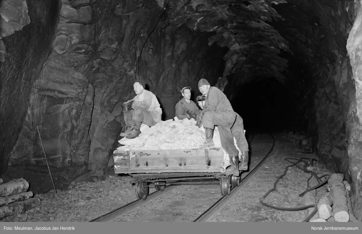 Steiner som er sprengt ut i forbindelse med strossingsarbeider er lastet over på tralle som her kjøres ut av Store Skiple tunnel mellom Reimegrend og Urdland stasjoner.