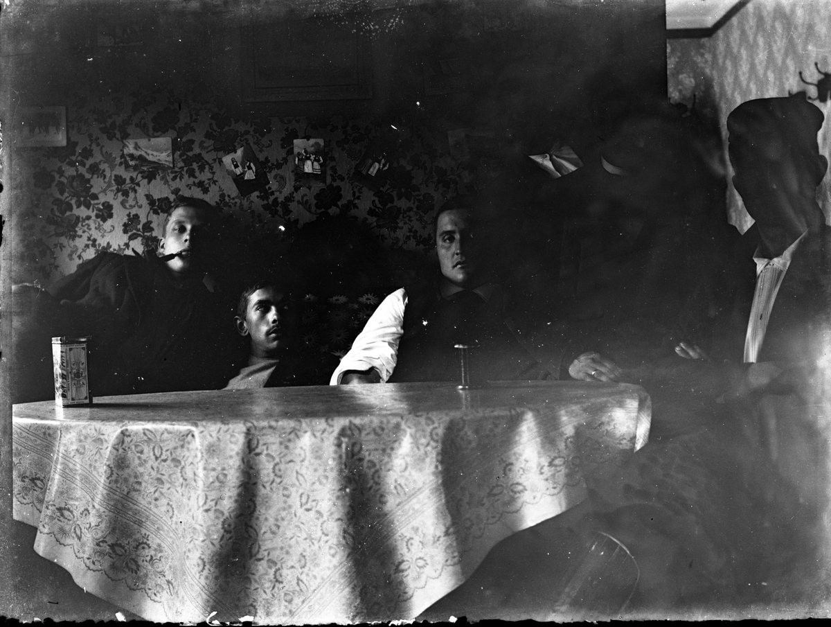 Unge menn rundt et bord i enkelt interiør.

Antatt fotosamling etter Anders Johnsen.