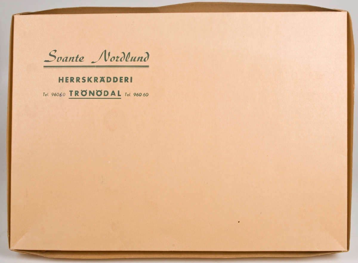 Skräddarkartong i gulvit papp med grönt tryck: "Svante Nordlund HERRSKRÄDDERI TRÖNÖDAL Tel. 960 60".