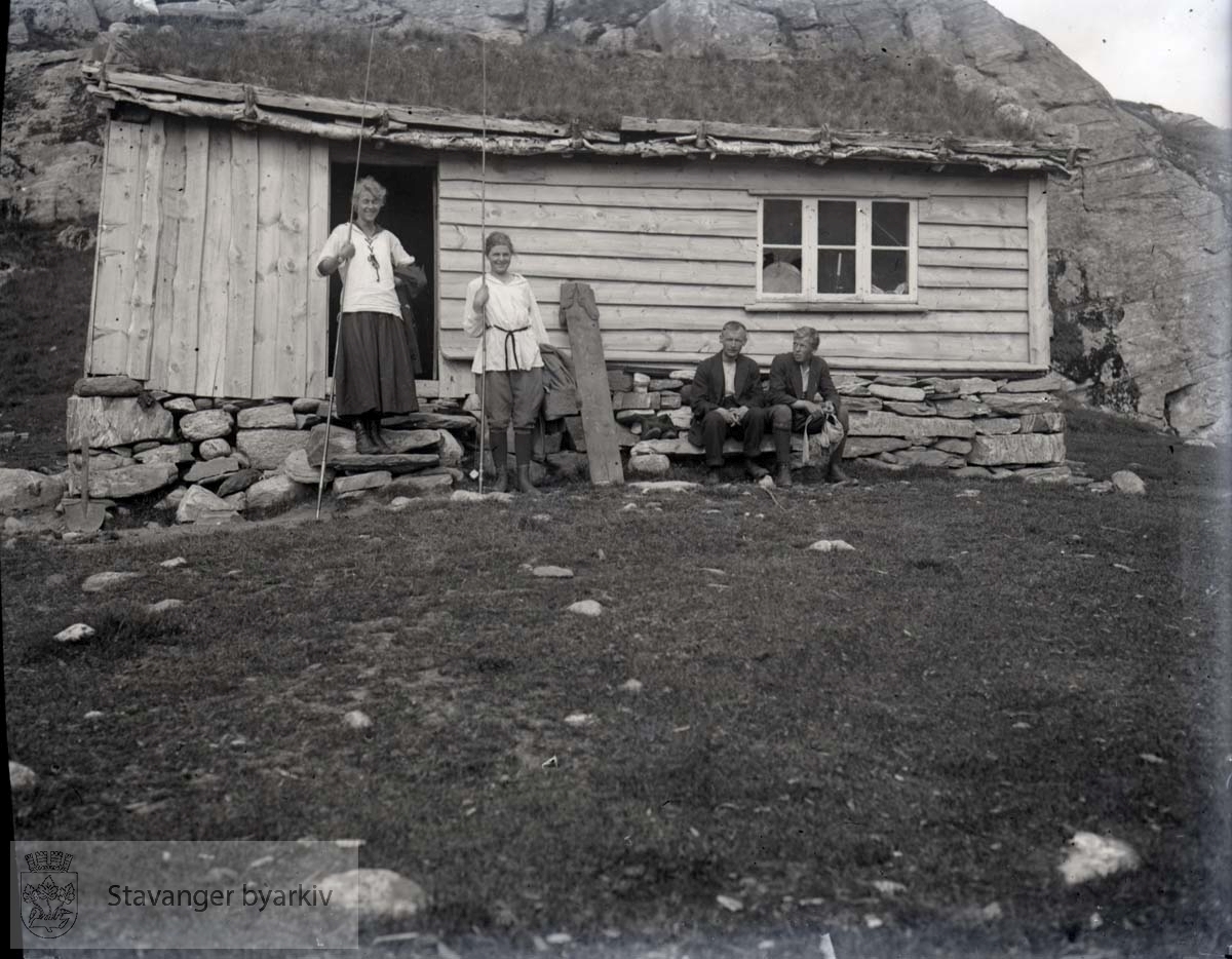 To kvinner og to menn utenfor hytte i fjellheimen