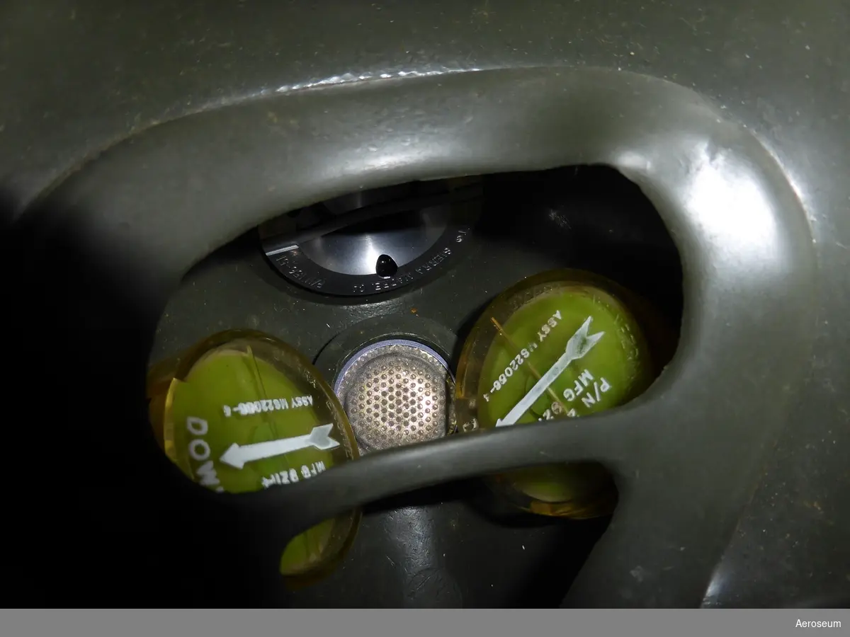 Syrgasmask med slang och centralanslutning i metall och gummi. Masken är mörkgrön med svart slang och blå centralanslutning.

På anslutningen står det: "BET F1230-310908 BEN CENTRALANSLUTNING URSPR- BET CVM-F1230-310908" och inristat i föremålet är: "11-1", "T-NR", och "340".

På Syrgasmasken står det: "MIL", "SILICONE", "[avhugget]SK, OXYGEN, PRESSURE BREATHING [avhugget]001[fyrkant]SMALL". Innuti masken finns det två gulgröna runda bitar där det stårpå båda: "SIERRA ENGINEERING CO SECO P/N 241-16 MFG 92114 [en pil] DOWN ASSY M822056-4". Det finns även ett metallstycke där det står: "SCOTT® SIERRA MADRE, CA P/N 156-51 MIL-V-251268 VALVE, OXY. EXHALATION, PRESS COMPENSATION".