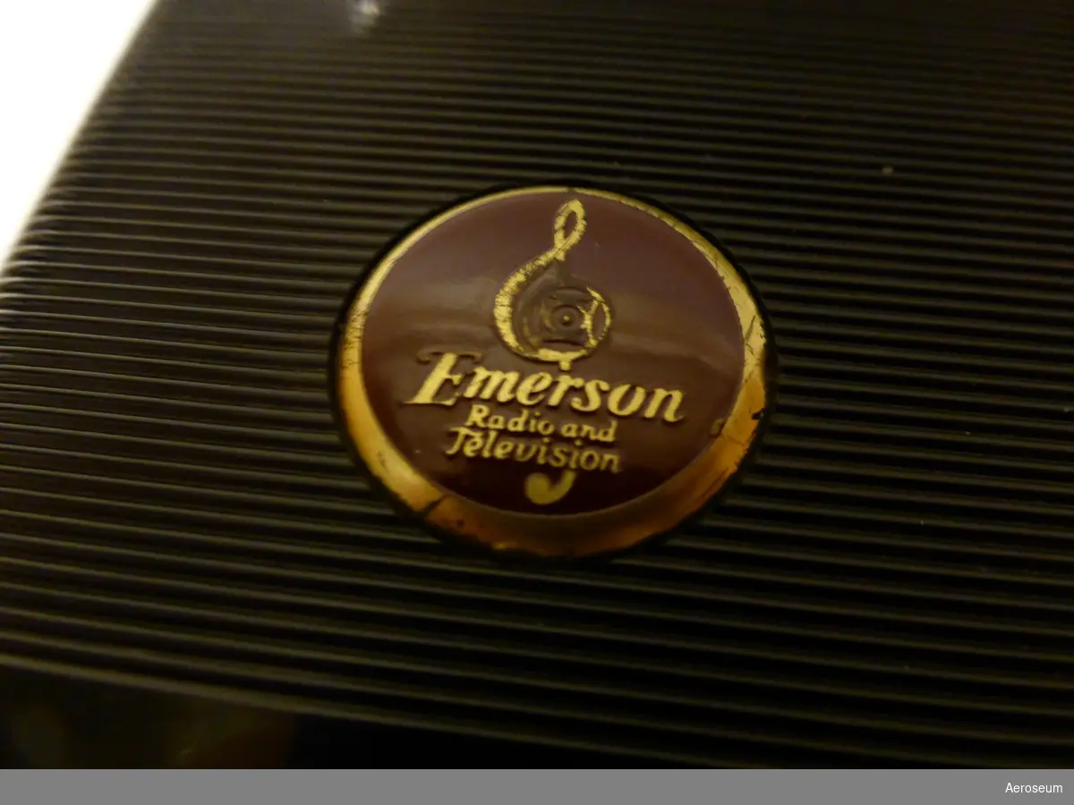 En brun och svart reseradio från 1946. Modell Emerson 508. Placerad i läderfodral som är i dåligt skick. Tillverkare: Emerson Radio and Television.
