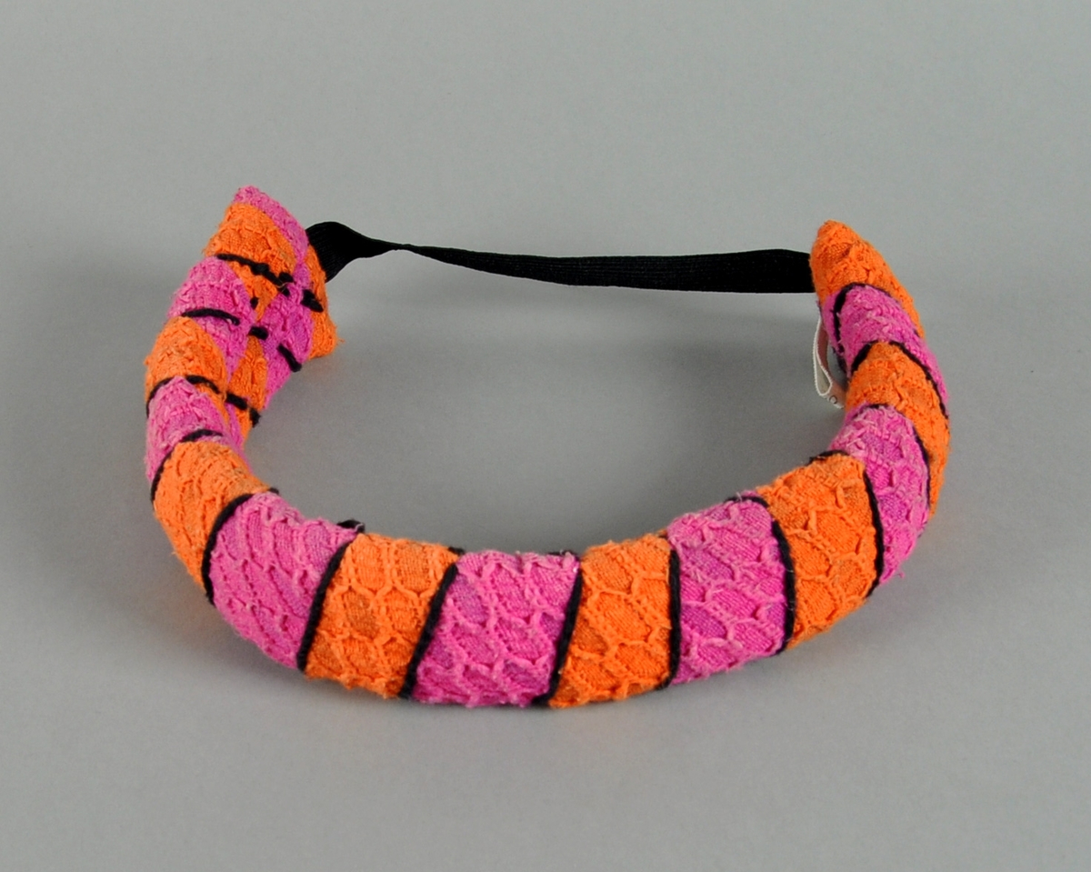 Strikket hårbånd i rosa, oransje og svarte striper, med elastikk midt bak.