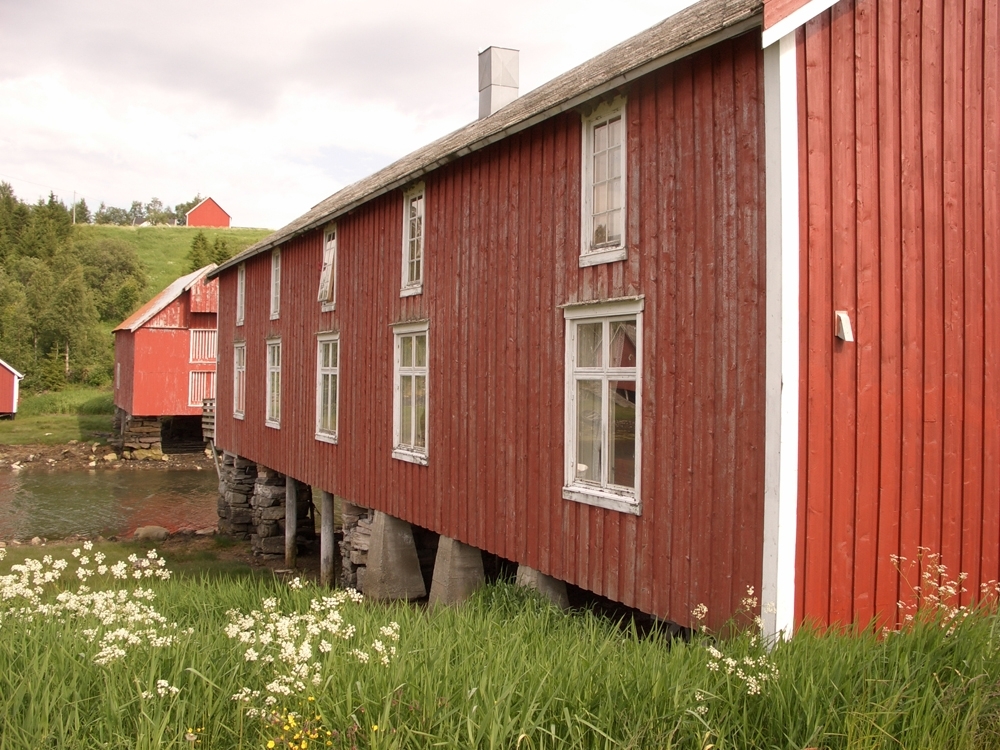 Leirfjord, Bardal, Wangbrygga. Langsiden på brygga med mange vinduer. Veggen og vinduene trenger skraping og maling.