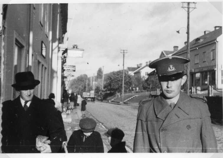 Brahegatan norrut, från torget. Mot fotografen går en äldre man i rock och hatt, två barn samt till höger en militär i uniform.