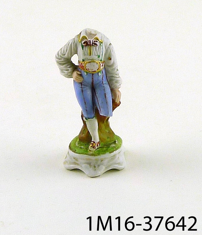 Figurin föreställande en pojke. Figurinen saknar huvud och ett av benen.