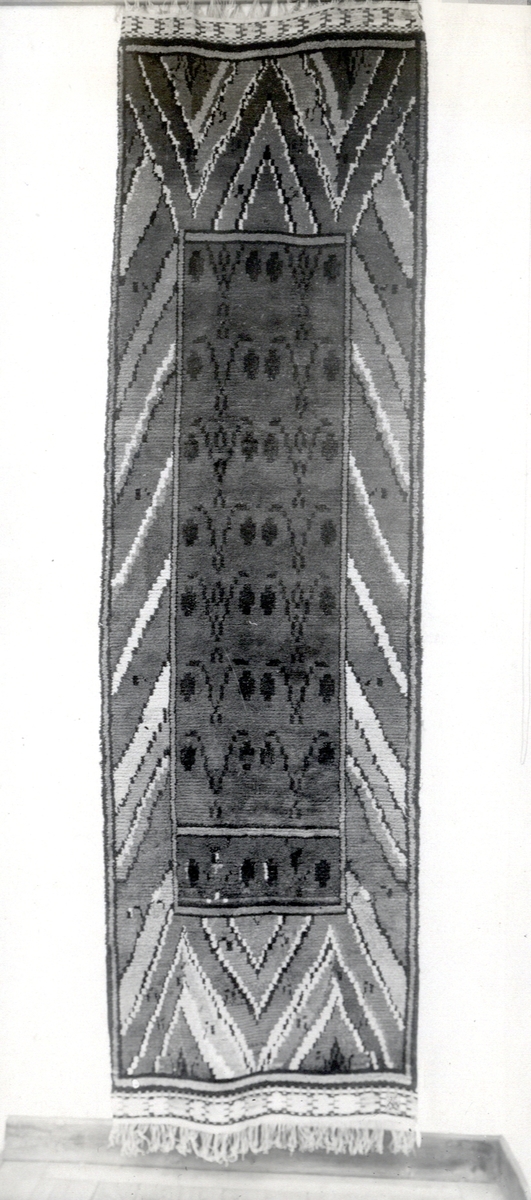 Foto (svart/vitt) av en ryamatta med geometriskt mönster (viggar m.m.). 
Inskrivet i huvudbok 1983.