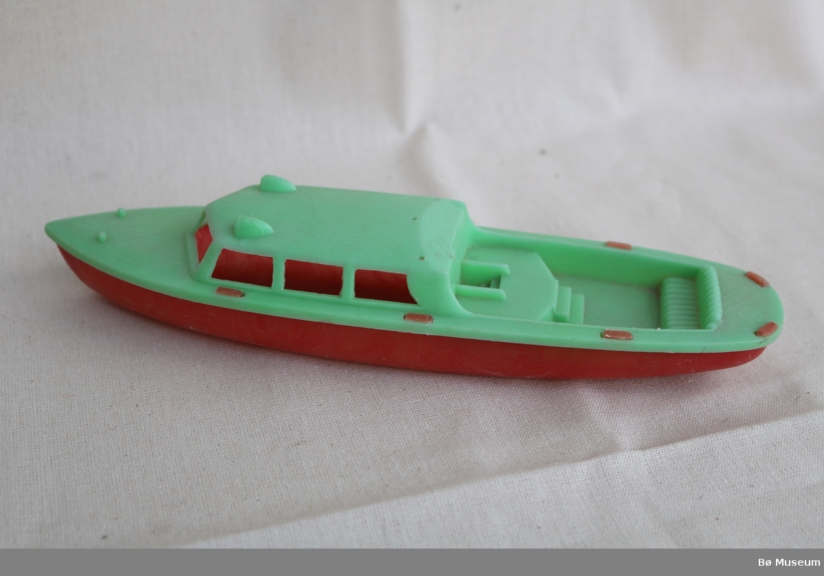 Leikebåt i plast med ljosegrøn topp og raudt skrog.