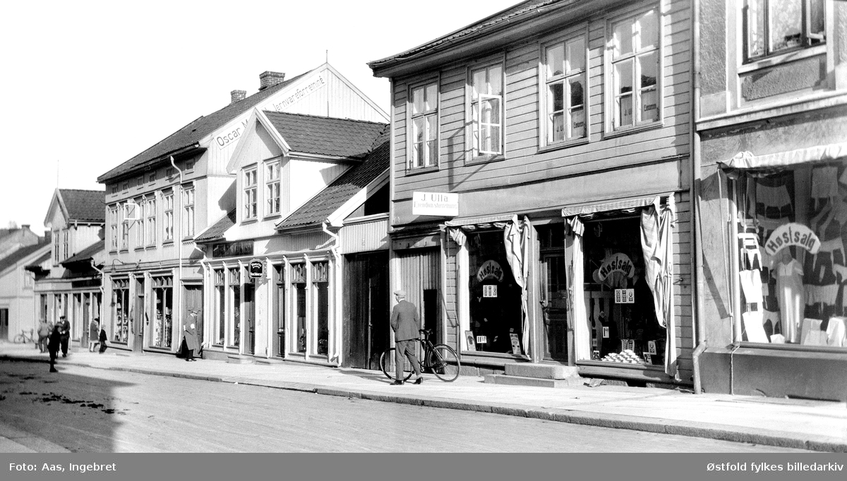 Gateparti fra Glengsgata i Sarpsborg i 1927. Partiet på østsida av gata mellom St. Marie gate og Pellygata. Fra høyre mot venstre: nr. 32 antakelig manufakturforretning, i vinduene reklame for "Høstsalg", på veggen skilt til J. Ulla Eiendomsforretning med kontor i 2. etasje, nr. 30 blomsterforretningen til .... Olsen, på gavlveggen i neste bygning nr. 28,  reklame for Oscar M... Jernvareforretning.