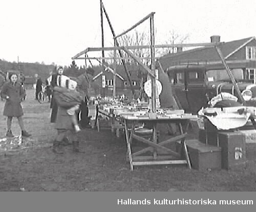 G25102 "Skällinge gamla marknadsplats ligger nu öde och tom."
G25104 "Ett par minnesgoda mannar, Edvard Nilsson, Attorp och Oscar Carlsson, Tågarp, vet mer om Skällinge marknad än någon annan." G25106 "En leksakshandlare - den ende på Skällinge marknad". 
Bilderna är publicerade i Hallands Nyheter 1947-12-17.