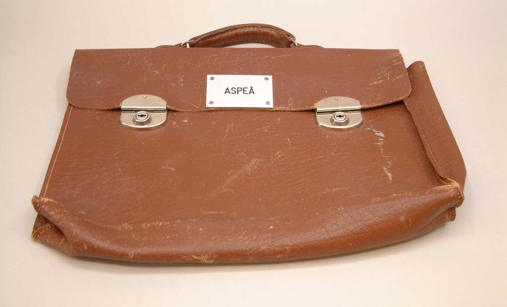 Portfölj av brunt läder med två lås.
En metallskylt med text "ASPEÅ"