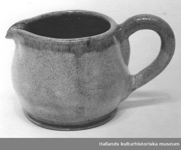 Kanna med öra och snip, av bränd keramik. Gulbrun melerad. I botten märkt "H Cederholm, Varberg 1969."