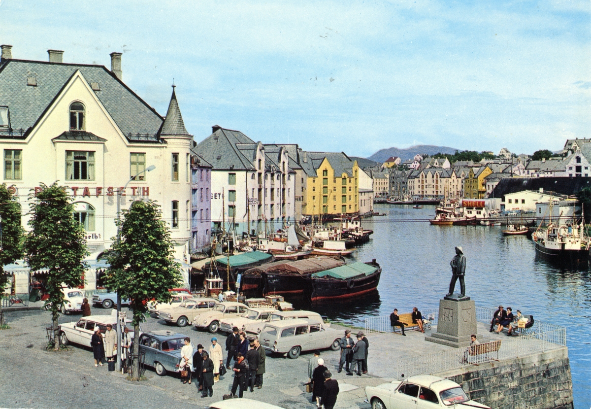 Oversiktsbilde av Brusundet i Ålesund, med Apotekertorget og statuen i forgrunnen. Flere biler er parkert på torget.