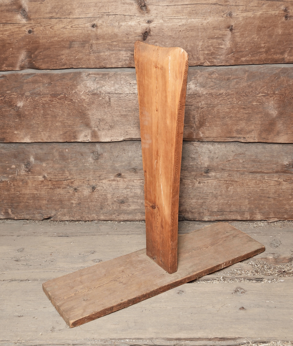 Skäktstol, skäktfot, tillverkad av trä. Rektangulär fot, vinkelställd bräda, upptill spetsig.