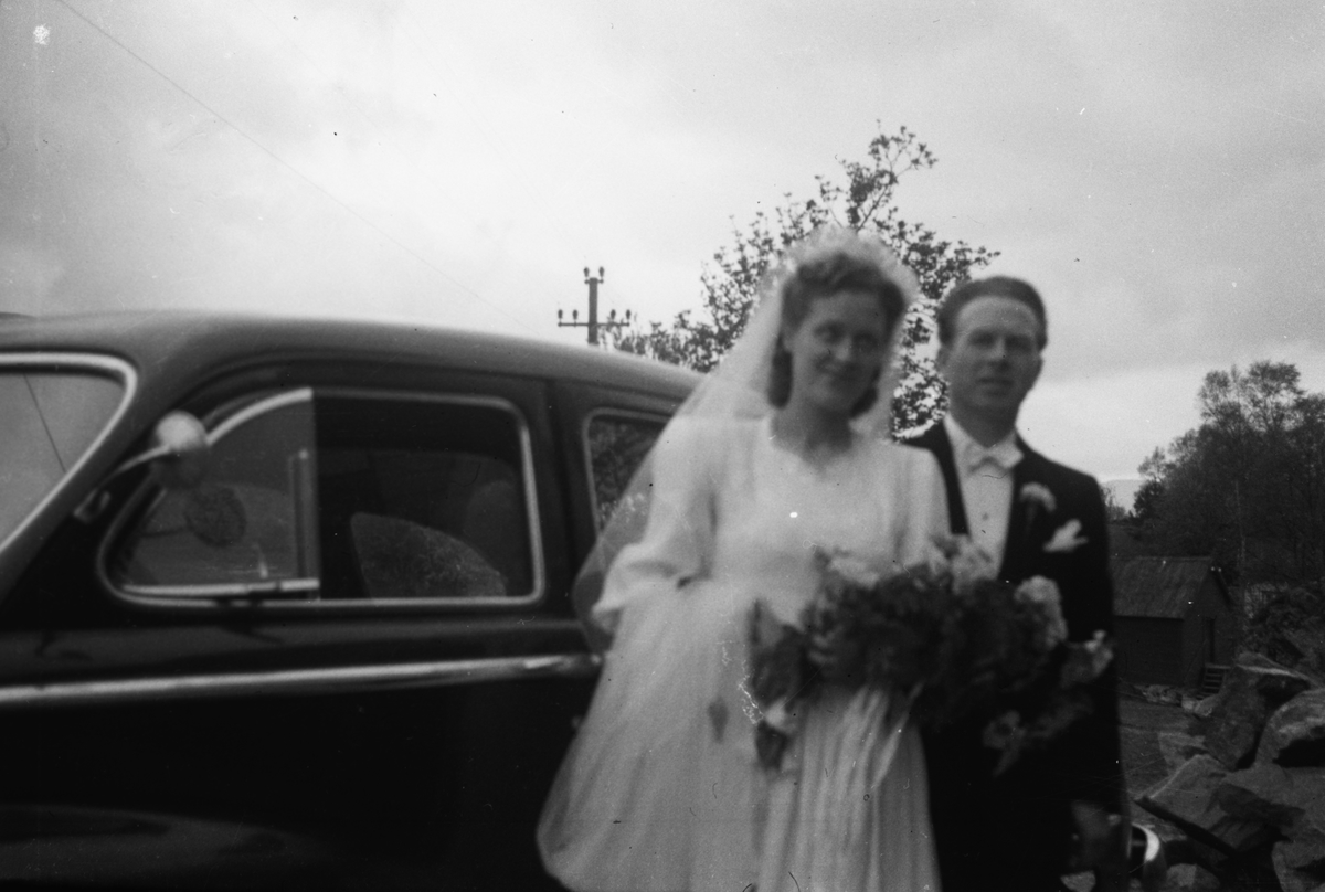Portrettfotografi av et brudepar foran en bil