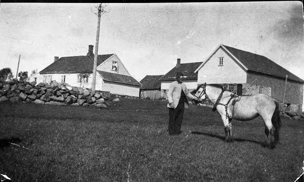 Mann og hest framfor garden på Løge, gnr. 15/bnr. 1. Bildet er frå 1915. Eigar av garden ernå (1986) Sven Ødegård (1932 - 1993)