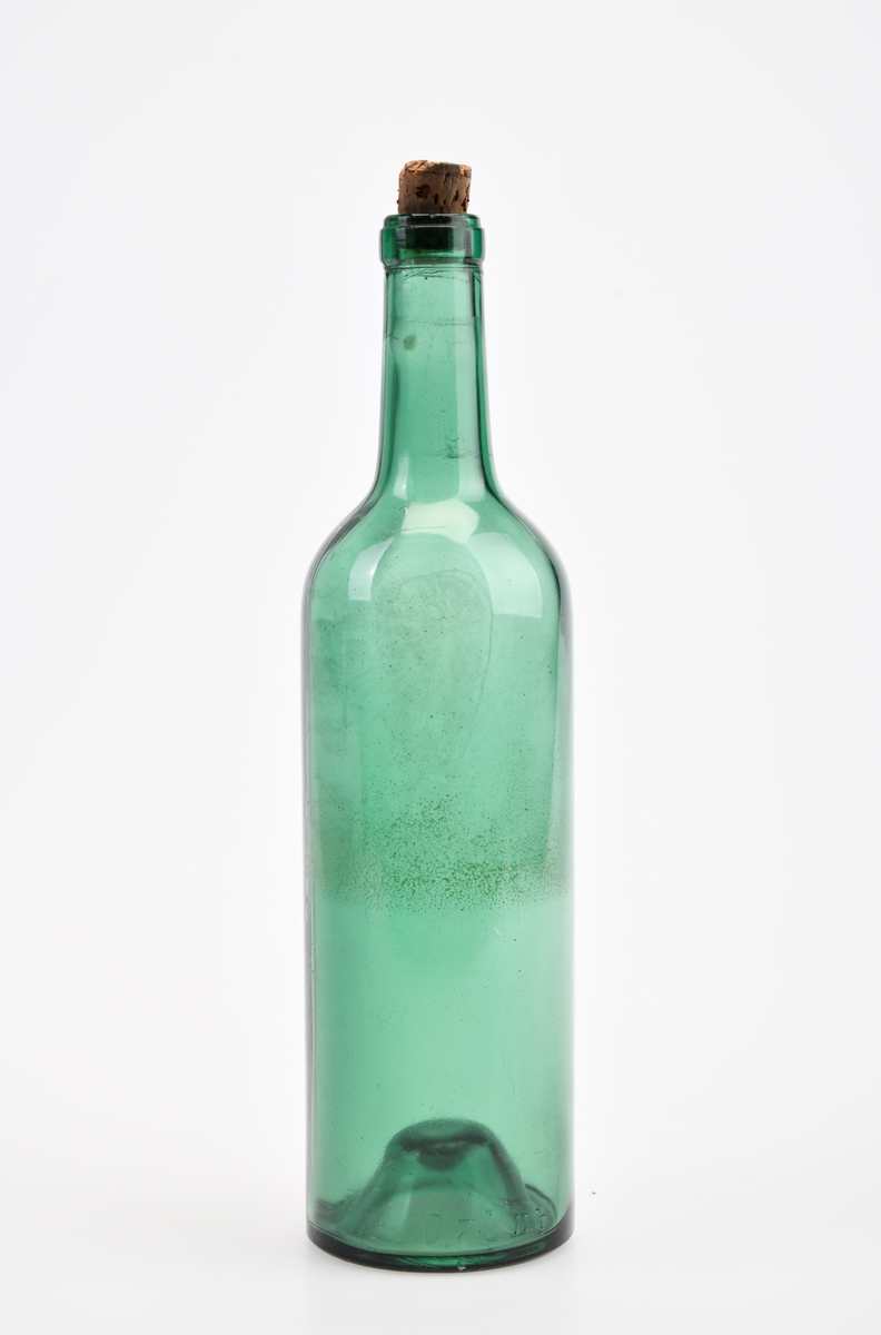 En glassflaske laget av grønt glass. I bunnen har den "tjuvbunn". I tuten er det brun naturkork. På toppen av korken er det blåfarge. På siden av flasken er det støpt inn tall/bokstaver, se "Påført tekst/merker".