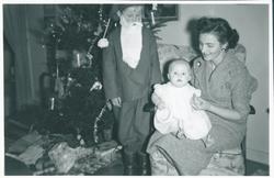 Mor med to barn sittende foran juletre.