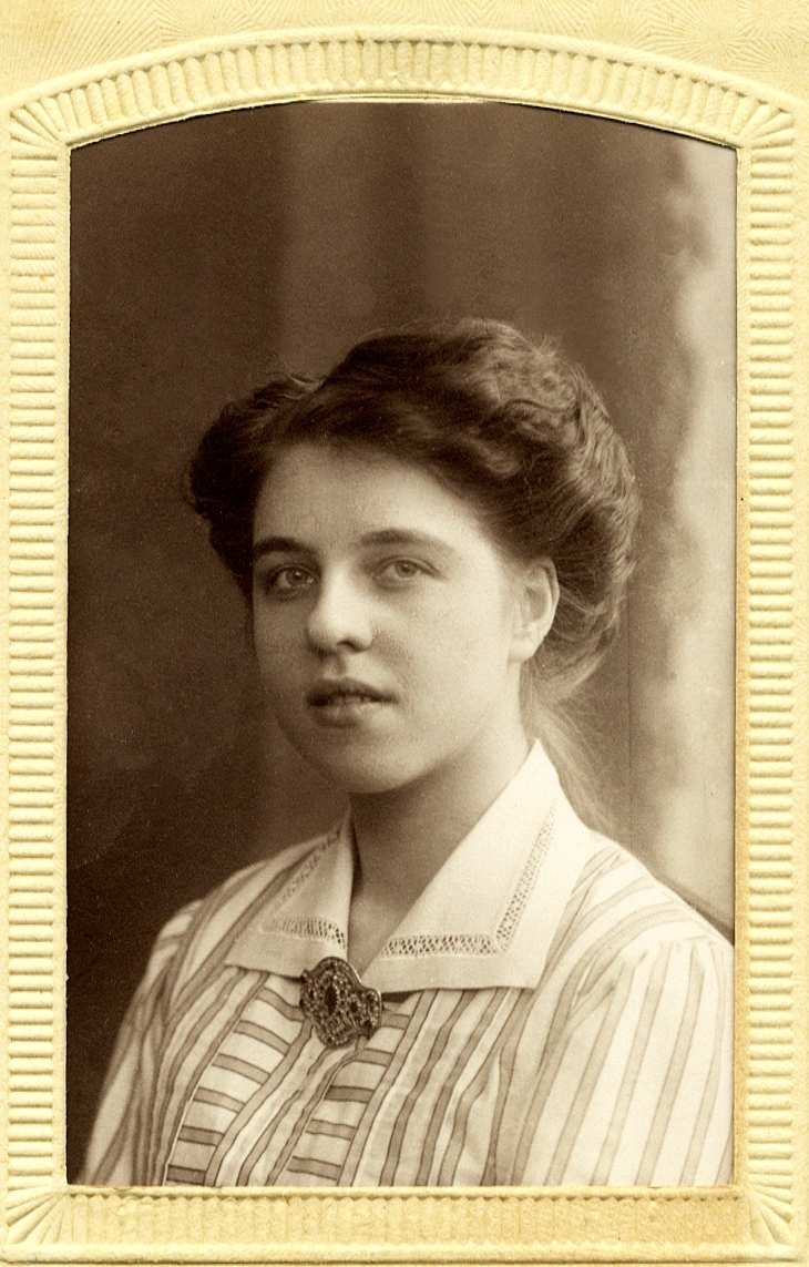 Foto av en ung kvinna i randig blus med vit krage. 
Bröstbild, halvprofil. Ateljéfoto.