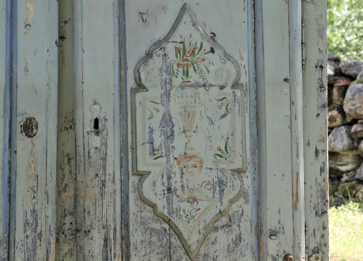 Skap med to låsbare dører. Malt i lyseblå, grålig farge og begge dørbladene dekorert.  men malinga er defekt.