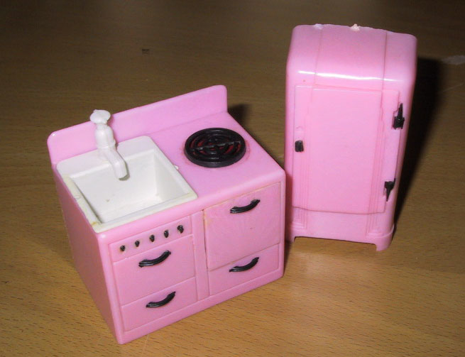 Rosa kjøkkeninventar av plast. Ett kjøleskap og en kombinert komfyr og vask med skuffer.