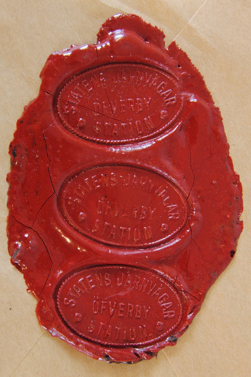 Tre sigillavtryck av rött lack på brunt papper. Avtrycken är formade som en liggande oval.