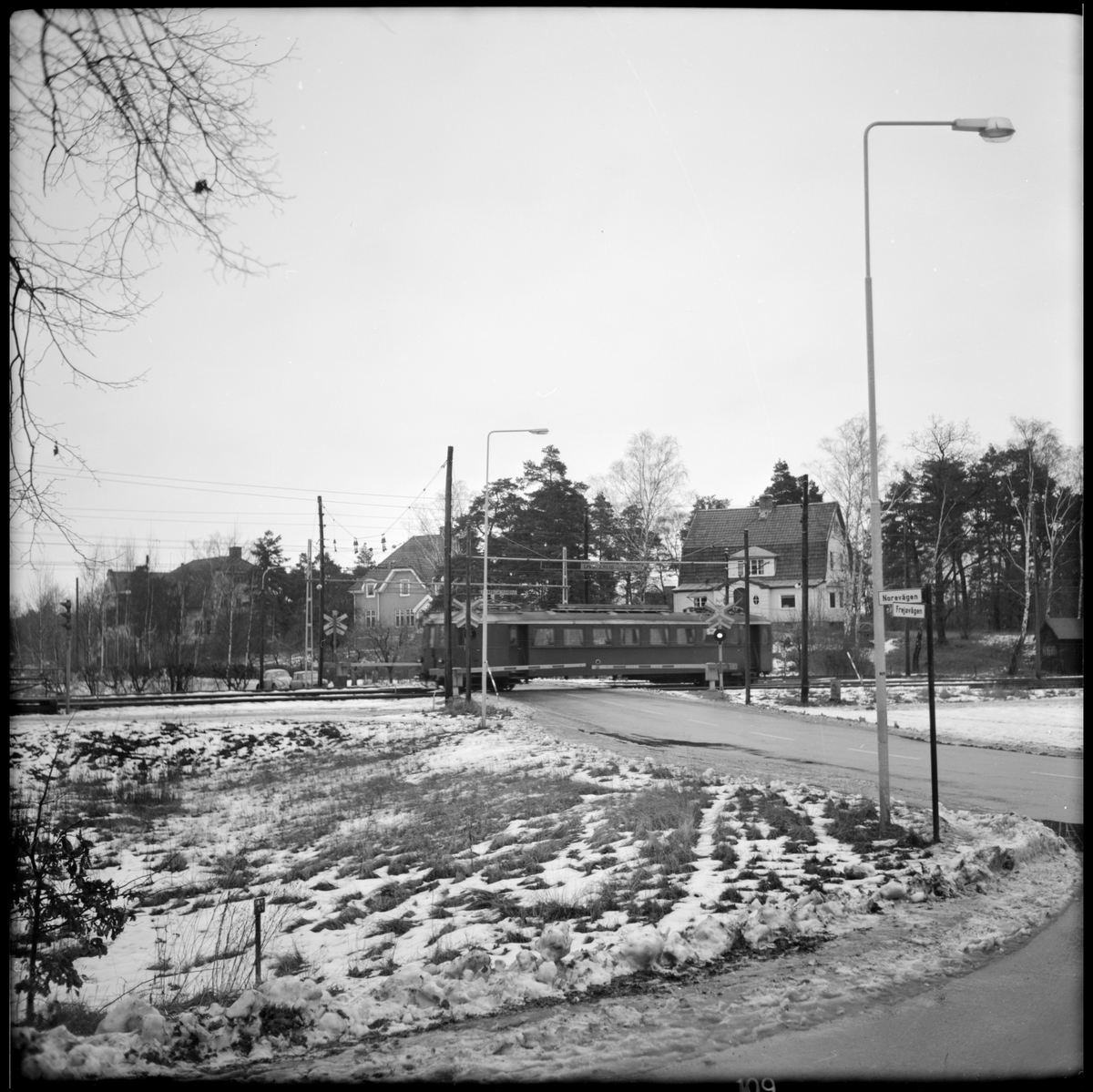 Motorvagn vid järnvägsövergången på väg in till hållplats Djursholm - Ösby i Stockholm.