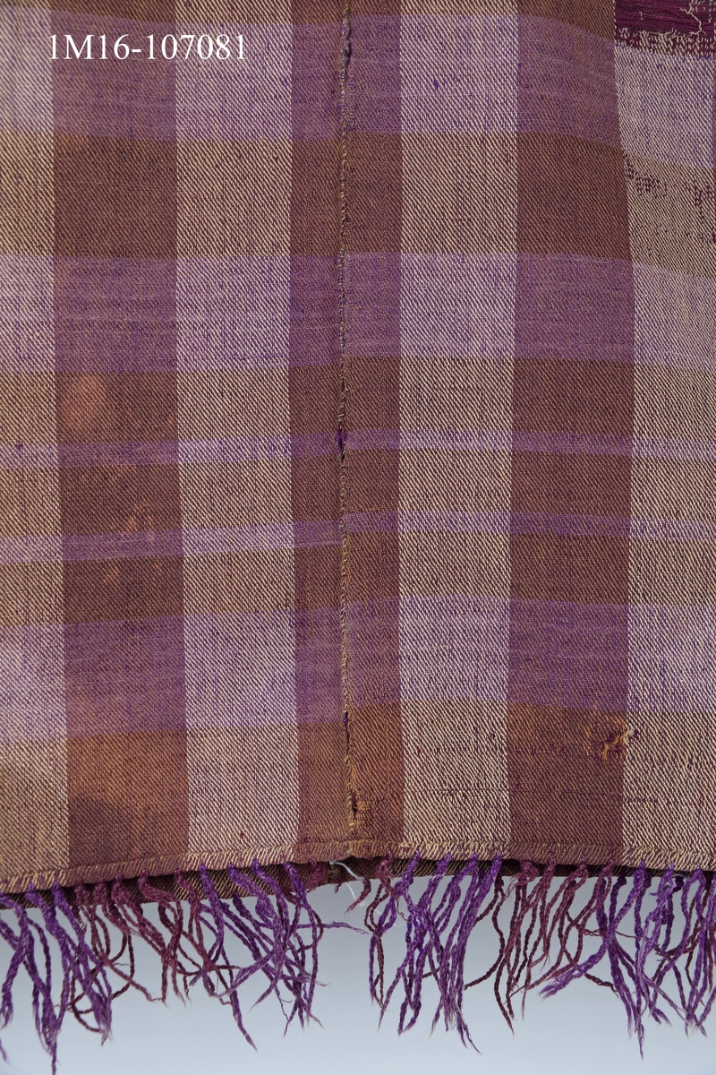 Schal i halvylle, brun, beige, och lila. Har tillhört Karl Edberg, Mjädrunga, Floby och använts som förlaga till schalen i Vilskedräkten.