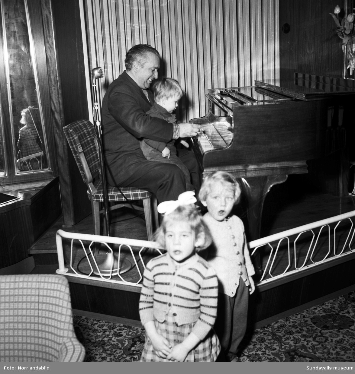 Konditori Terrassen på Tivolivägen 22. Pianisten Tony Ferraresi sitter vid pianot med ett litet barn i knät.