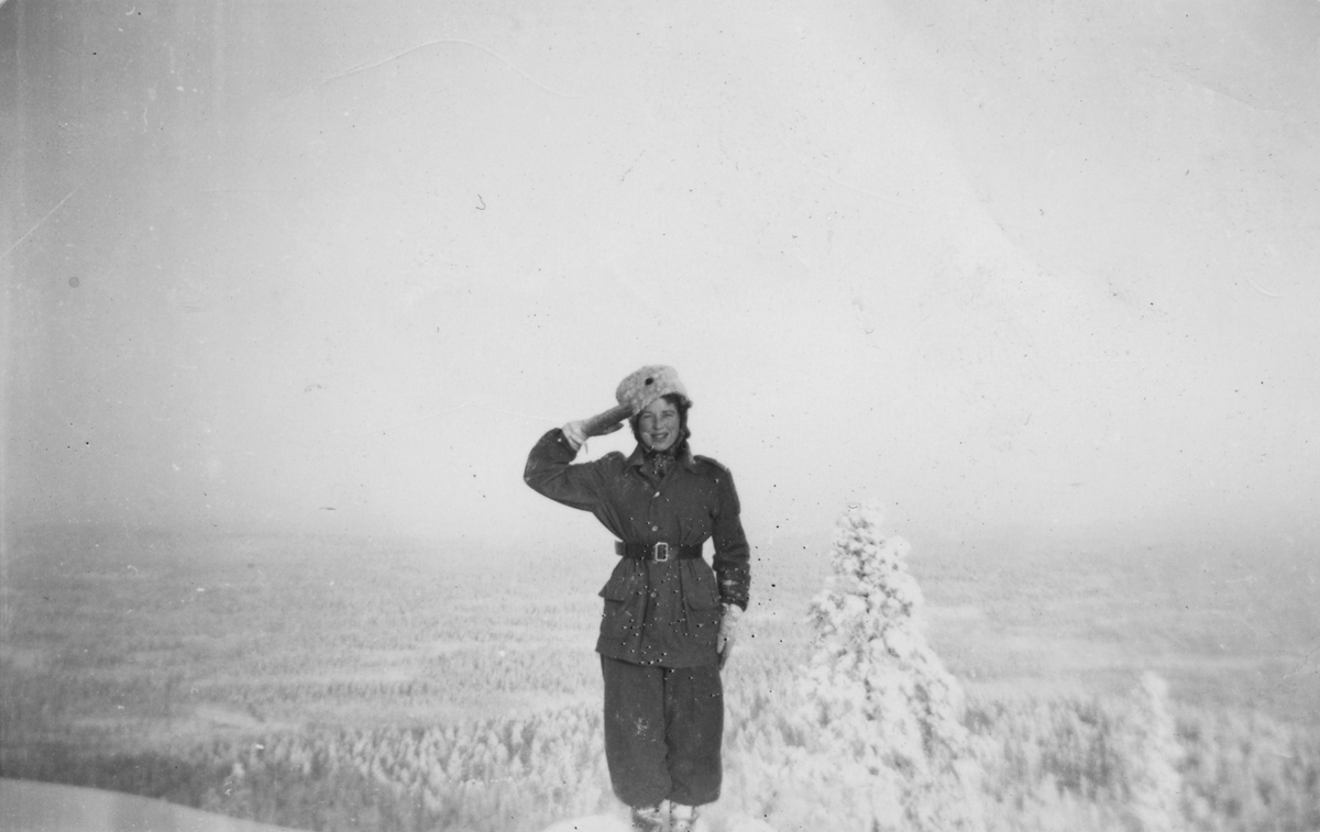 Luftbevakare Karin Nordberg i uniform på en bergstopp under en skidtur i fjällen, 1942. Karin gör honnör. Karin Nordberg tillhörde 91:a ls-kompaniet i Tellejåkk, Kåbdalis under beredskapsåren.
