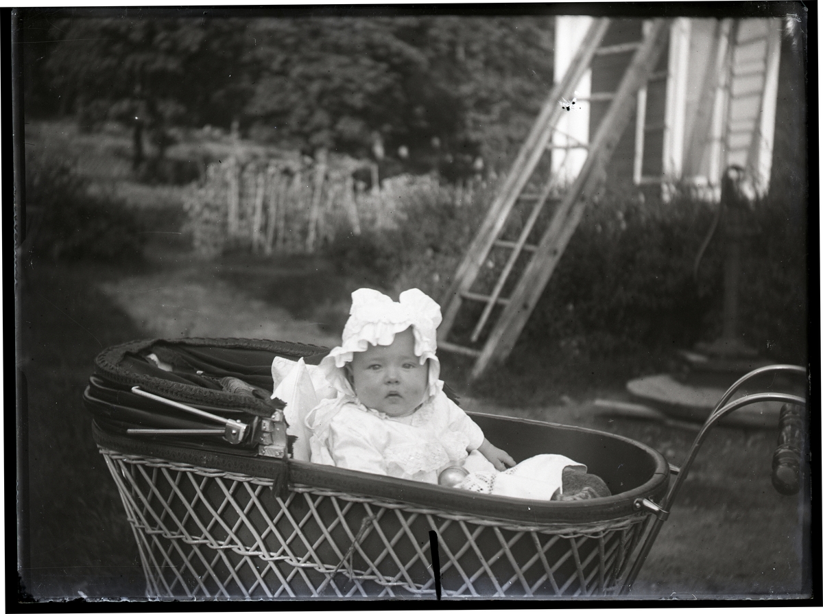 Maja Lindgren i barnvagn i trädgård, Dalarna.