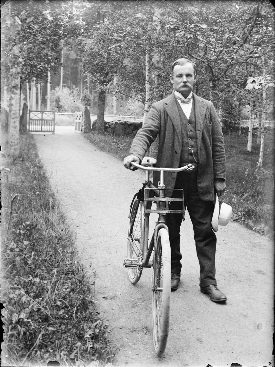 Man med cykel i trädgård, Alunda, Uppland