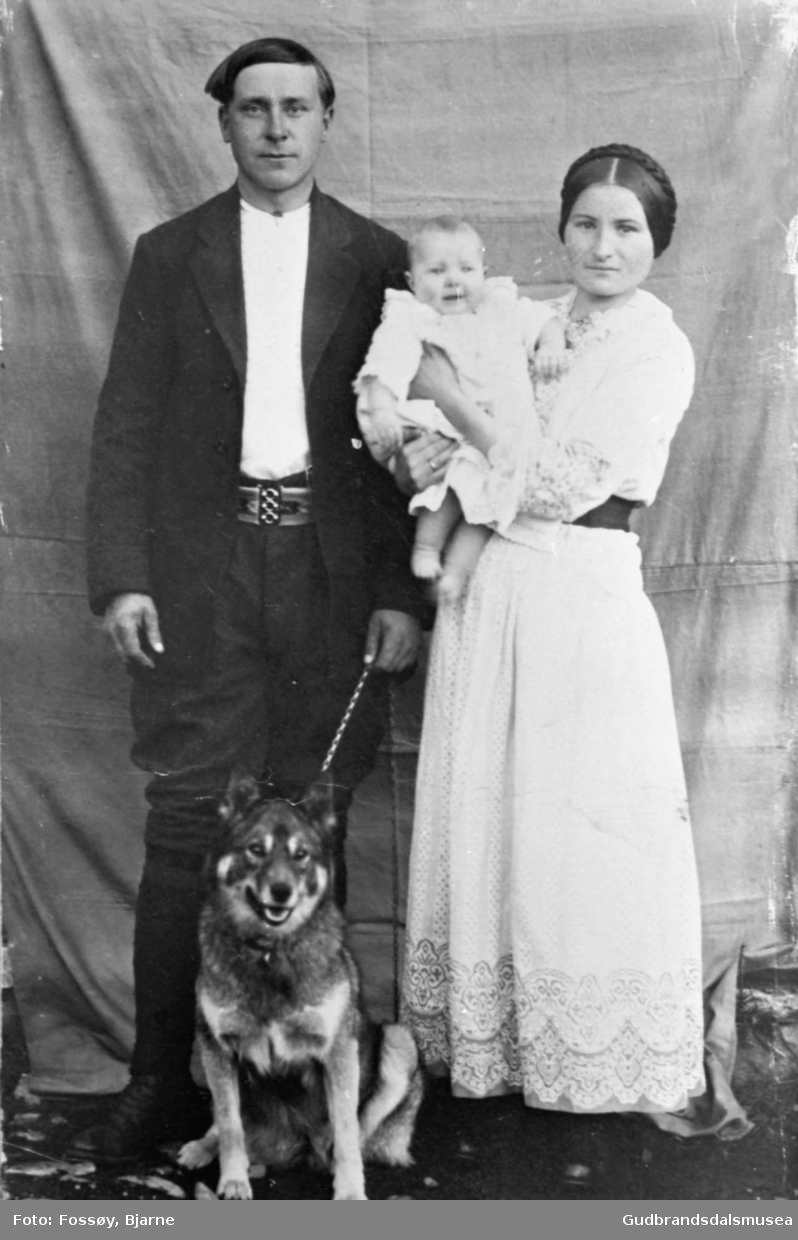 Portrett, familien Dahl; mann og kvinne med lite barn på armen, hund sitter ved deres føtter. 