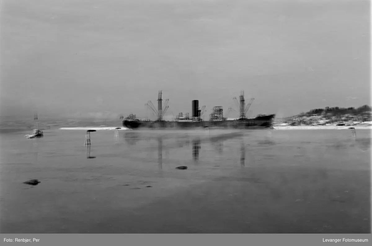 Tysk forsyningsskip med antiluftsskyts akter i havneområdet på Levanger