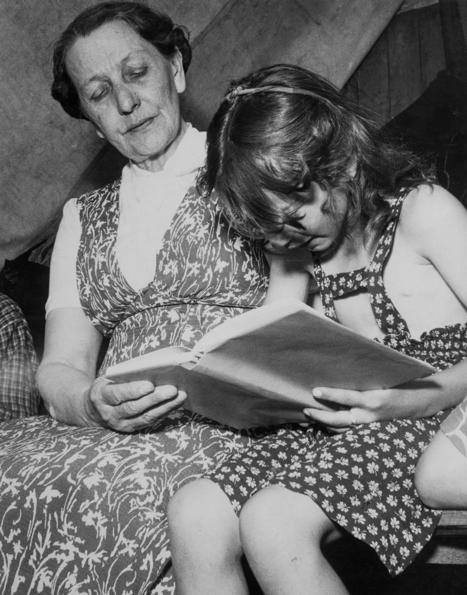 Lärarinnan hjälper en flicka att lära sig läsa från en ABC-bok. Undervisningen sker i en sommarskola för romska barn, 1950.