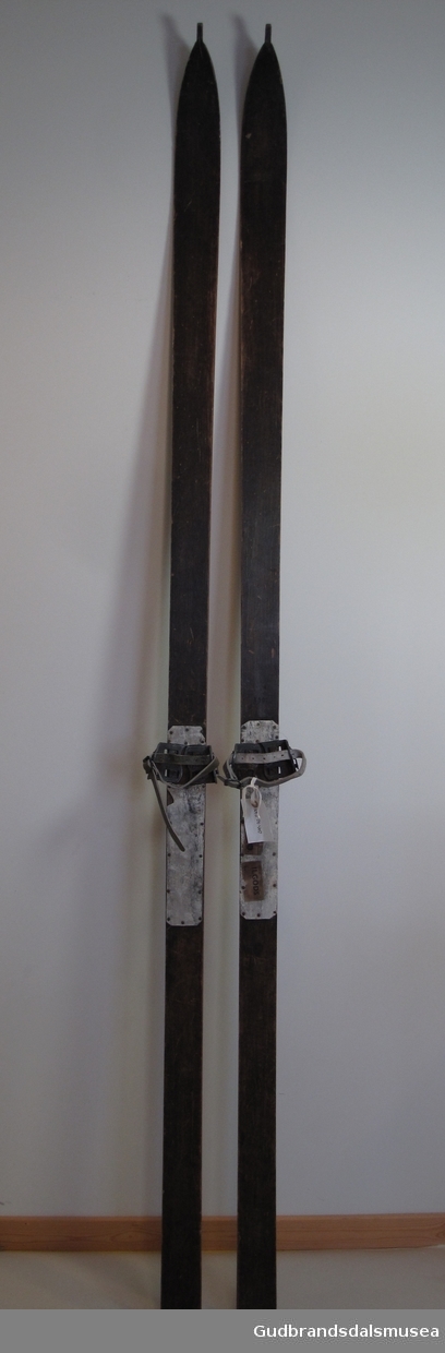 Lange fjellski i tre fra 1920-tallet. Flat overside. Avsmalende framski/svakt innsvinget form. Tupp med "sukkerbit". Sirkulær rand. Plan, rett avskåret bakende. Tåjern med lærstropper for feste rundt støvlesnuter, "Thorleif Haug bindinger", oppkallt etter skiløperen med samme navn. Bindingstypen kalles også Bergendahlsbindinger, patentert av Oluf Selmer i 1913; regnes for å være den første langrennsbindingen. Bindingen har fått navn etter Lauritz Bergendahl som dominerte langrennsporten 1910-20. På fotsteget påspikret tynn plate av ukjent materiale.