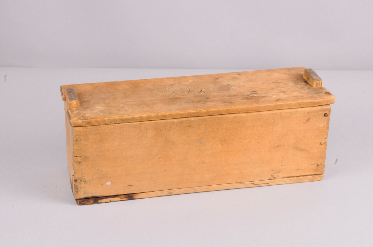 Rektangulær kasse med lok, nagla saman med trenaglar, lok med innskorne initsialar.