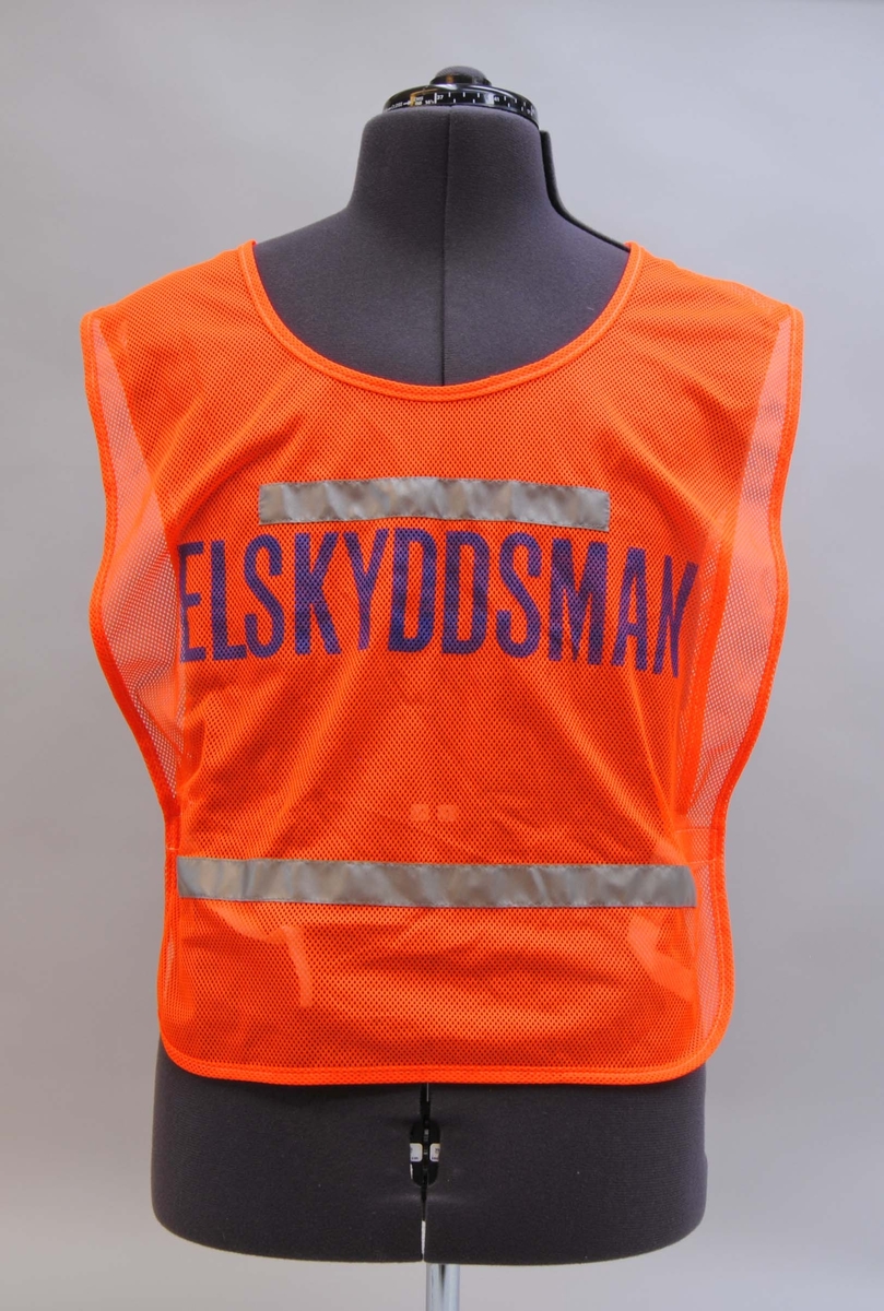 Orange varselväst av reflexväv med texten "ELSKYDDSMAN" i blått på fram- och baksidan. Två rader med reflexband, ovanför och nedanför texten. På sidorna finns vit kardborrknäppning.
